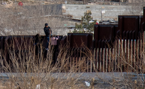 After jumping the U.S.-Mexico border wall in Sunland Park, New Mexico, a man sits atop the wall, aiding two others climbing back over to the Mexican side. 